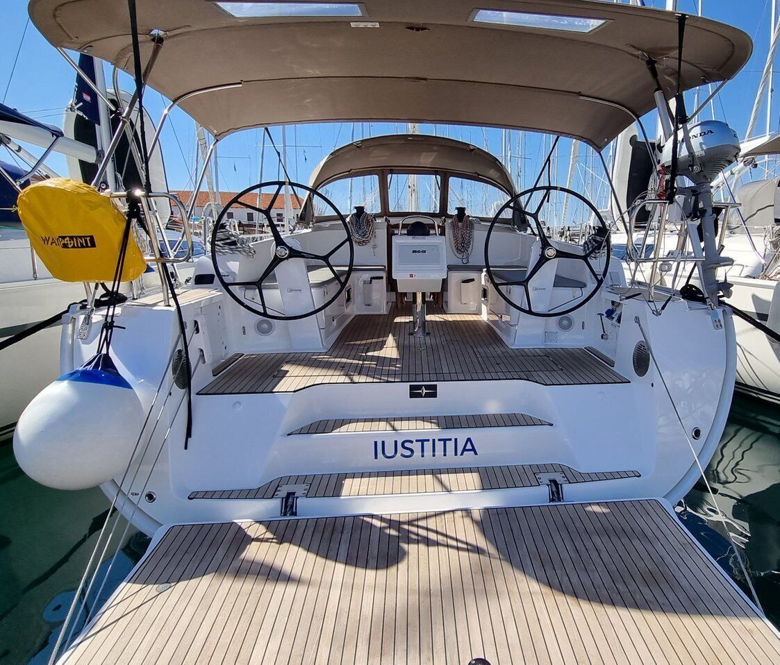 A boat deck with the name 'Iustitia' on the bow, steering wheel, and a yellow life buoy.