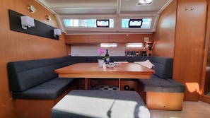 A modern interior with a central table, cushioned seating, a small kitchen area, and a large window. - Sun-kissed Sailing Adventure in Split-Dalmatia, Croatia (Trogir)