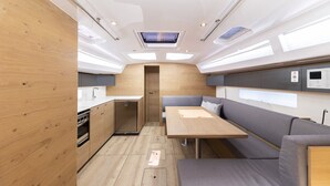 A compact kitchen with a built-in oven and a small refrigerator, a dining area with a table and benches, and a skylight above. - Sun-Kissed Sailing Adventure in Zadar, Croatia (Zadar)