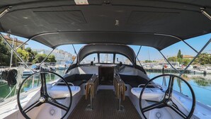 A boat's interior with a steering wheel, two side tables, and a view of the marina. - Sun-Kissed Sailing Adventure in Zadar, Croatia (Zadar)