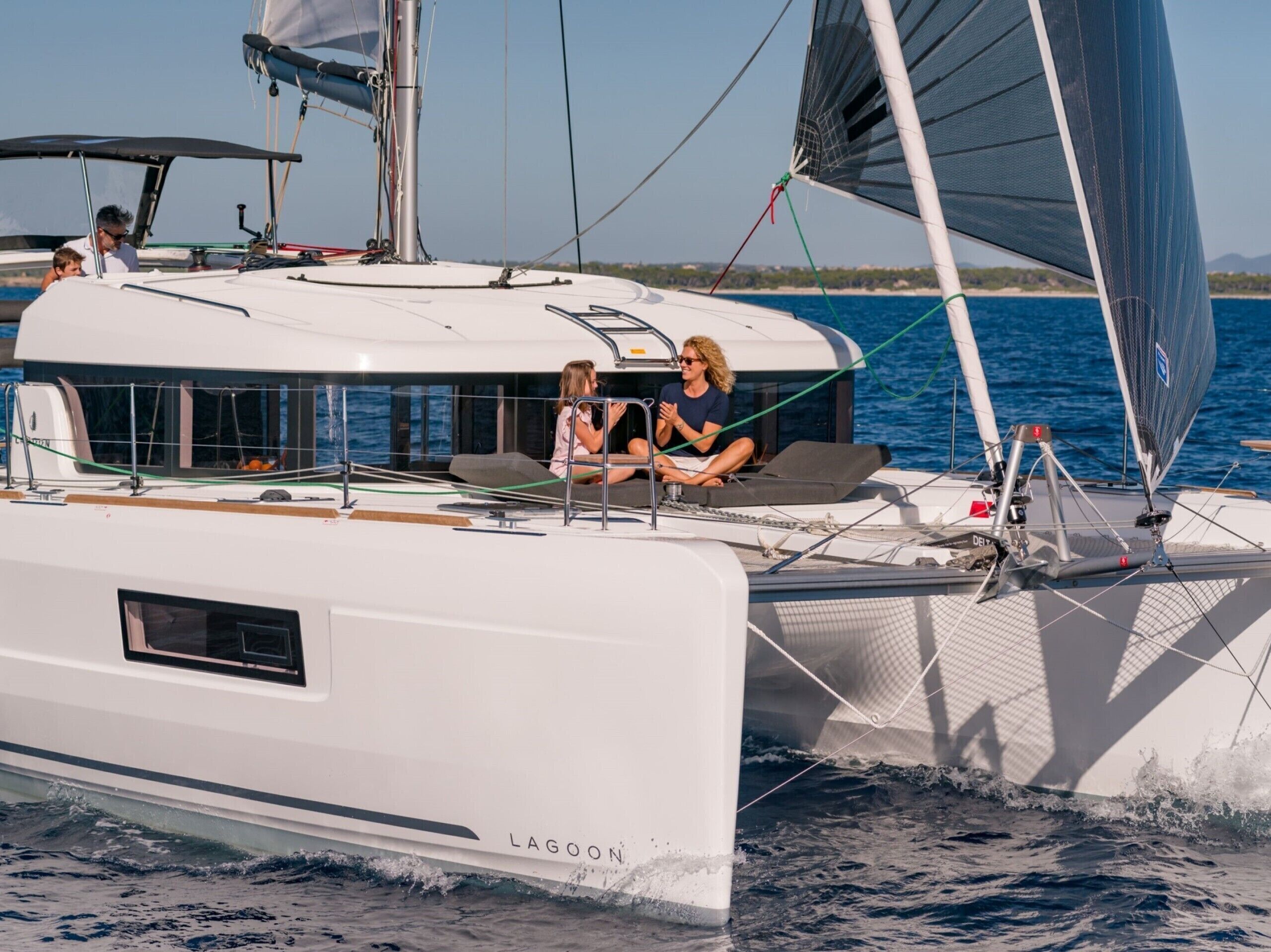 Un velero con camarote, asientos en la cubierta y una persona al timón.