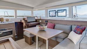 A modern interior with a dining area, seating, and a view of the sea. - Sun-Kissed Sailing Adventure in Islas Cícladas, Mykonos (Mykonos)