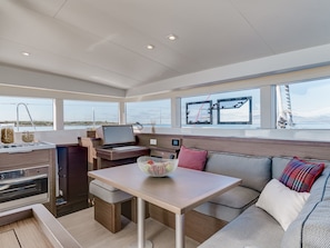A modern interior with a dining area, seating, and a view of the sea. - Sun-Kissed Sailing Adventure in Islas Cícladas, Mykonos (Mykonos)