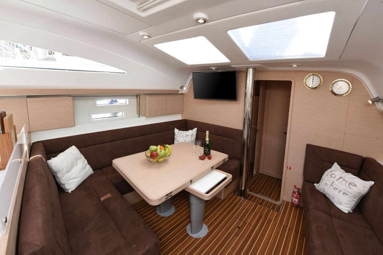 A compact, well-lit interior with a dining area, seating, and a TV mounted on the wall.