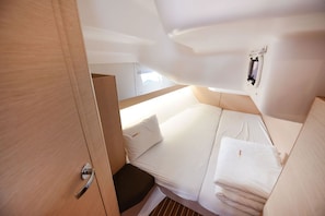 Habitació petita i ben il·luminada amb un llit, una petita banca i una làmpada penjada a la paret.