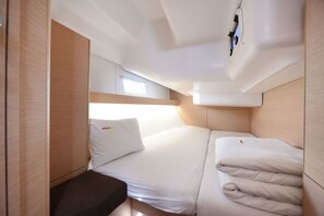 Una cabina compatta e ben illuminata, con un letto, un piccolo angolo salotto e una finestra che lascia entrare luce naturale.