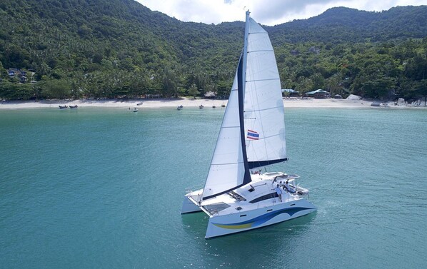Un velero en un mar tranquilo con montañas al fondo.