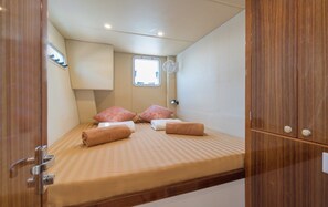 Un dormitorio pequeño con una cama individual, una ventana discreta y un armario de madera.