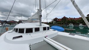 Eine weiße Yacht liegt in einer Marina vor der Kulisse von Gebäuden und Palmen.