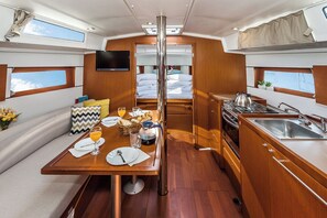 A compact interior with a dining area, kitchenette, and a bed with a view. - Sun-Kissed Sailing Adventure in Zadar, Croatia (Biograd na moru)
