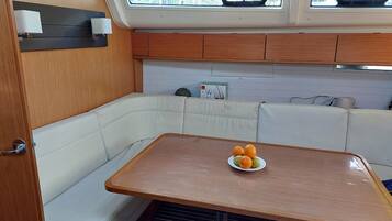 A compact kitchen area with a wooden table, white cushioned seating, and a small window with a view.
