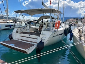 A yacht docked at a marina with a covered deck, a steering wheel, and life buoys.