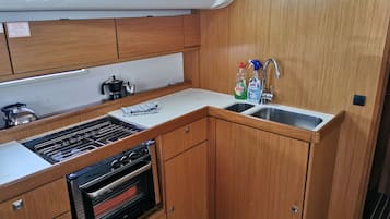 A compact kitchen with wooden cabinets, a built-in oven, a sink, and a window above the countertop.