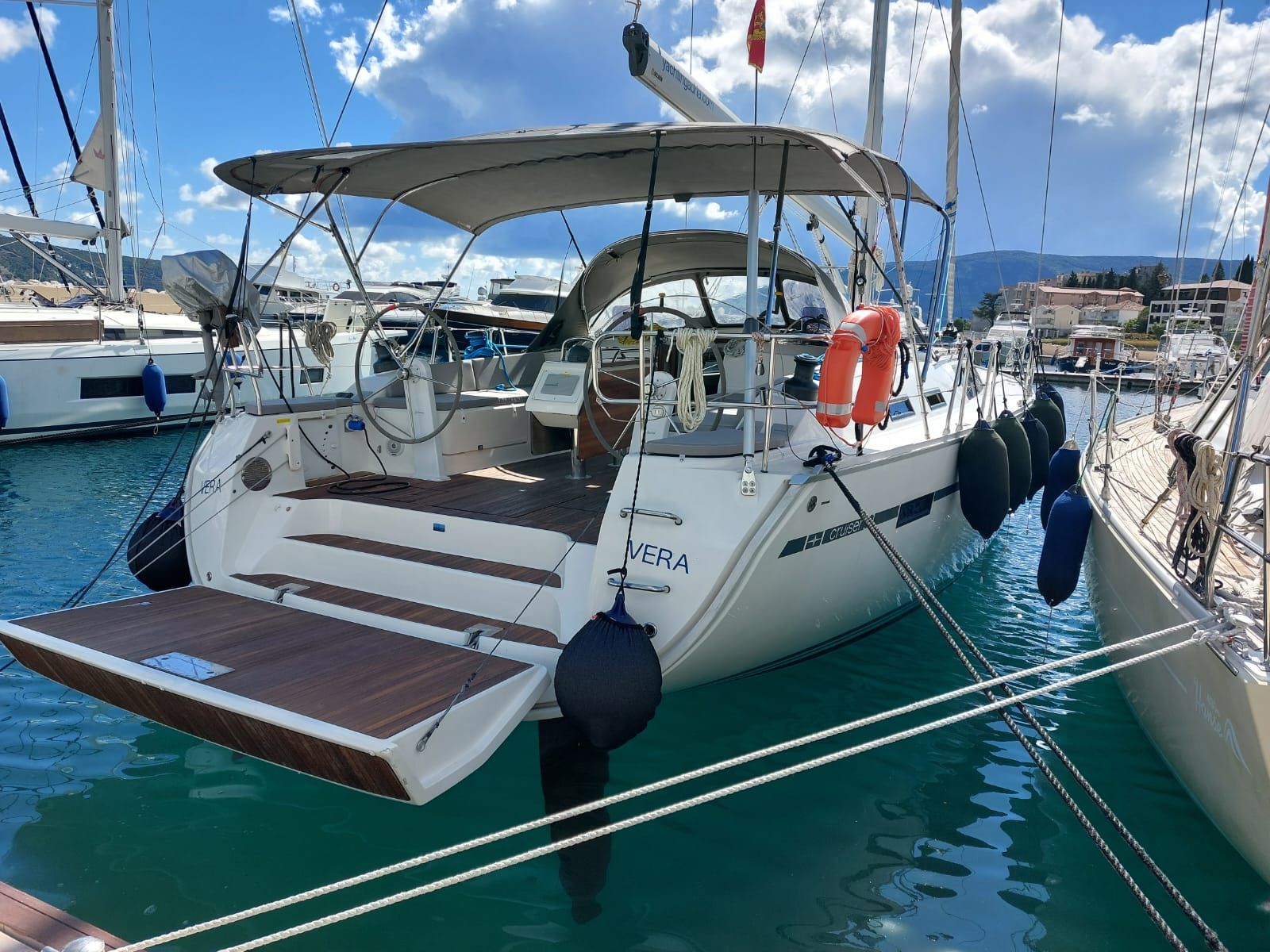 A yacht docked at a marina with a covered deck, a steering wheel, and life buoys.