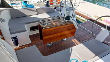 A boat's deck with a seating area, a control station, and a life preserver.