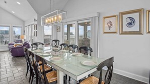 A dining area with a glass table, chairs, and a pendant light.