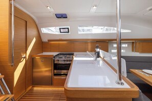 A compact galley with a stove, sink, and seating area, featuring wooden cabinetry and skylights. - Sun-Kissed Sailing Adventure in Zadar, Croatia (Zadar)