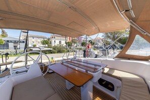 A boat deck with a cushioned seating area, a small table, and a steering wheel. - Sun-Kissed Sailing Adventure in Zadar, Croatia (Zadar)