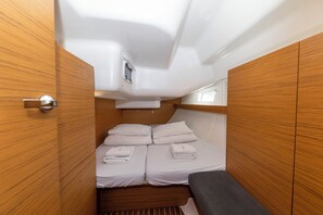A compact, well-lit cabin with a bed, a bench, and wooden paneling. - Sun-Kissed Sailing Adventure in Zadar, Croatia (Zadar)