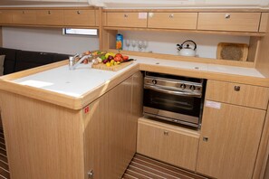 Una kitchenette funcional con un lavabo, estufa y armarios de almacenamiento.