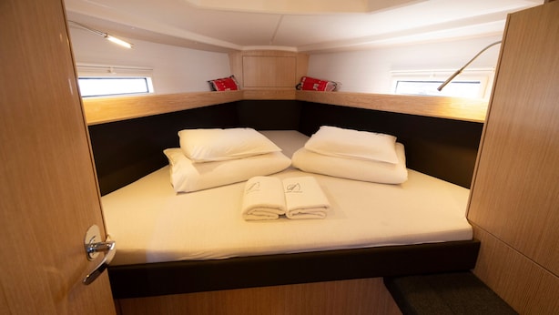 Une cabine compacte et bien éclairée, dotée d’un lit superposé, d’une petite fenêtre et d’une tête de lit en bois.