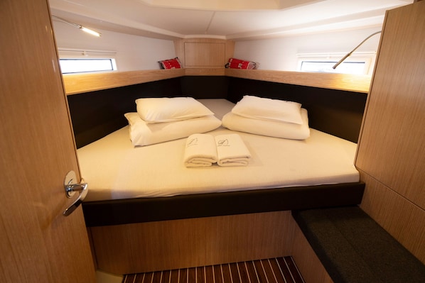 A compact, well-lit cabin with a bunk bed, a small window, and a wooden headboard.