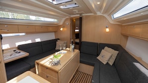 Un intérieur compact et bien éclairé, avec un canapé, une petite table sur laquelle se trouve une bouteille, et un meuble en bois.