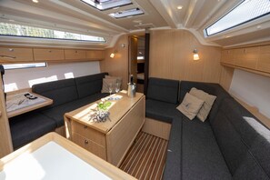 A compact, well-lit interior with a sofa, a small table with a bottle, and a wooden cabinet.