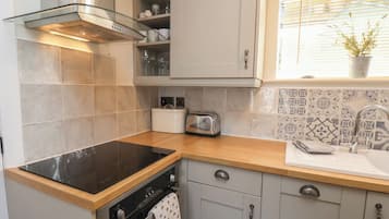 A kitchen with a black stovetop, a built-in oven, a toaster, and a sink with a patterned backsplash.