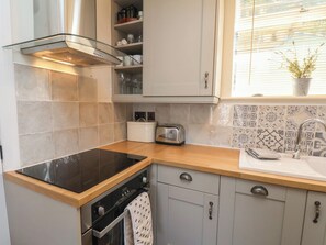 A kitchen with a black stovetop, a built-in oven, a toaster, and a sink with a patterned backsplash.