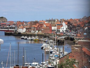 A harbor with boats docked, buildings with red roofs, and a clear sky. - 4 Studley Terrace (Whitby)
