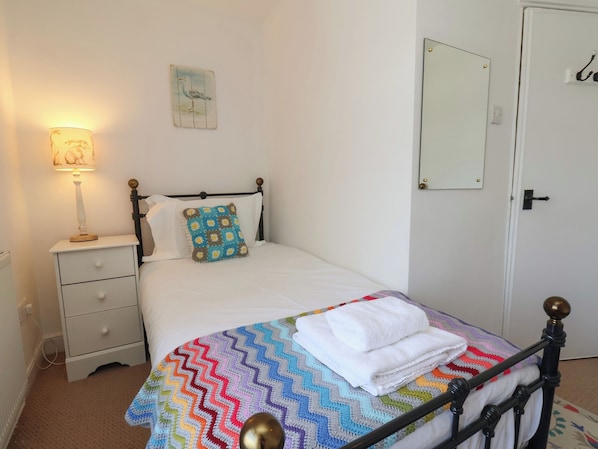 A bedroom with a bed, a nightstand, a lamp, a mirror, and a door.