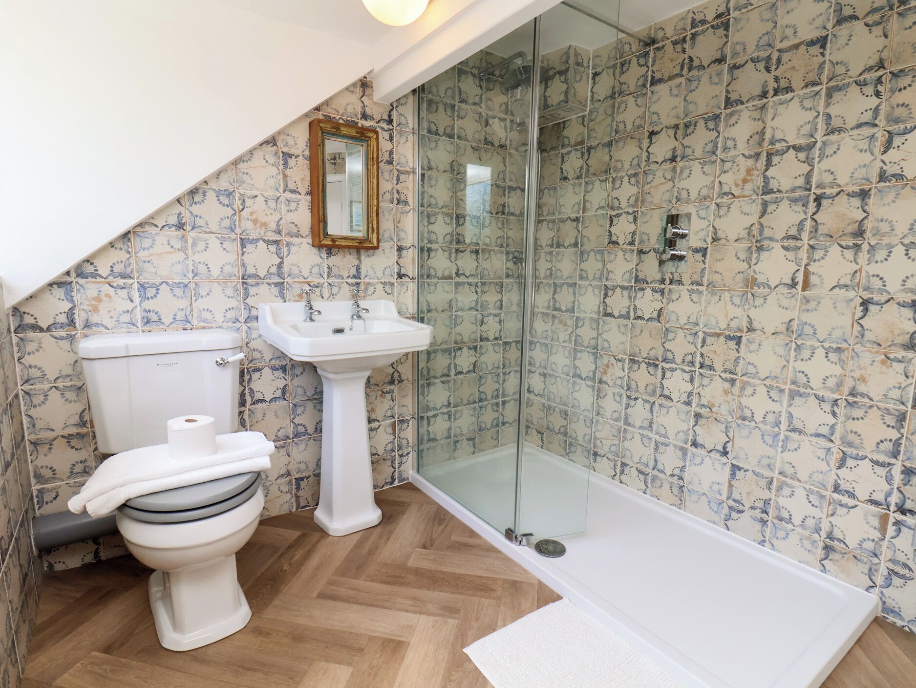 A bathroom with a toilet, sink, shower, and a mirror.