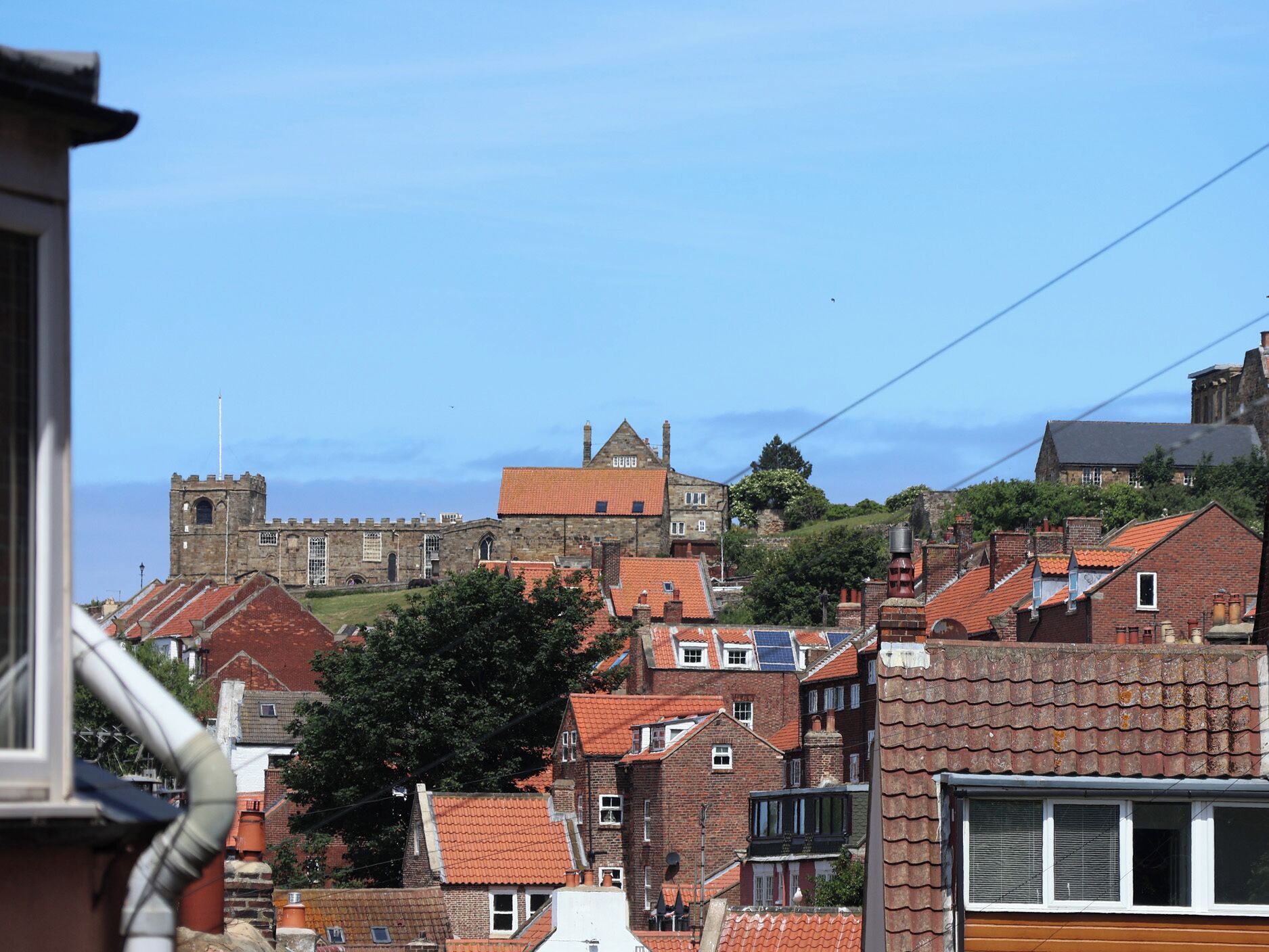 A historic building with a prominent tower, surrounded by residential buildings with red-tiled roofs.