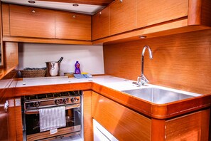 A compact kitchen with wooden cabinetry, a stainless steel sink, and a built-in oven. - Sun-Kissed Sailing Adventure in Sibenik, Croatia (Primošten)
