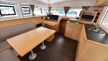 Een compacte keuken met een eethoek, een ingebouwde oven en een raam met uitzicht op de jachthaven.