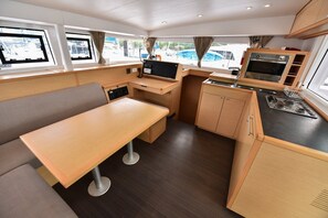 A compact kitchen with a dining area, a built-in oven, and a window with a view of the marina. - Sun-Kissed Sailing Journey in Trat, Koh Chang (Ko Chang)