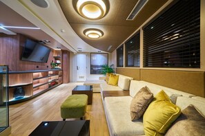 Ein modernes Interieur mit Sofa, Hocker, Fernseher und Regalen.