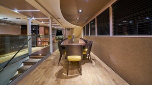 Un interno moderno con soffitto curvo, un tavolo rotondo al centro con sedie, una scala e una finestra con persiane.