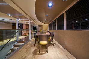 Ein modernes Interieur mit gewölbter Decke, einem runden Tisch in der Mitte mit Stühlen, einer Treppe und einem Fenster mit Jalousien.
