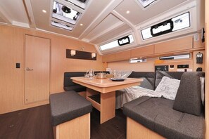 A compact interior with a dining table, cushioned seating, and overhead lighting.