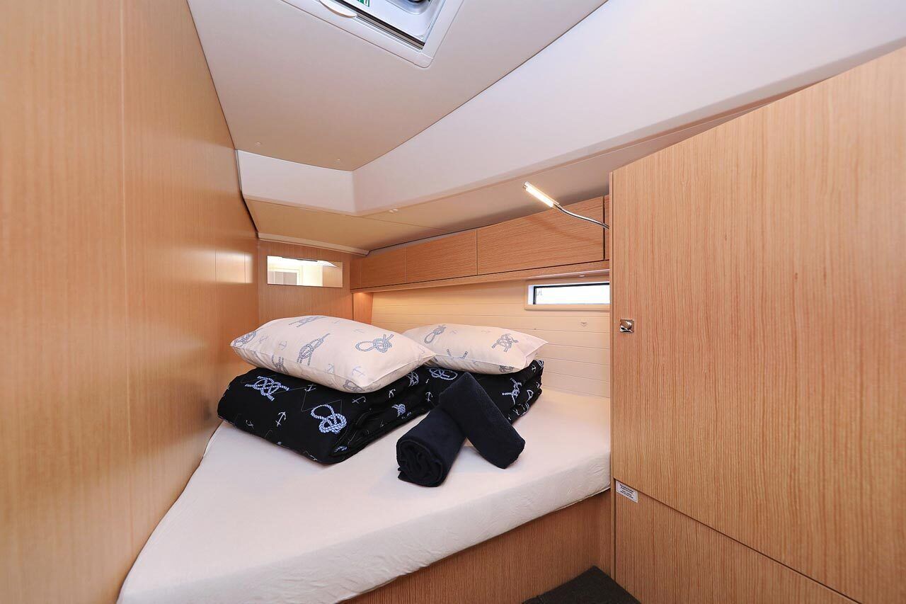 A compact room with a bed, wooden walls, a skylight, and a small window.