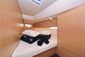 A compact room with a bed, wooden walls, a skylight, and a small window.