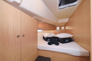 A compact room with a bed, a small window, and a television mounted on the wall.
