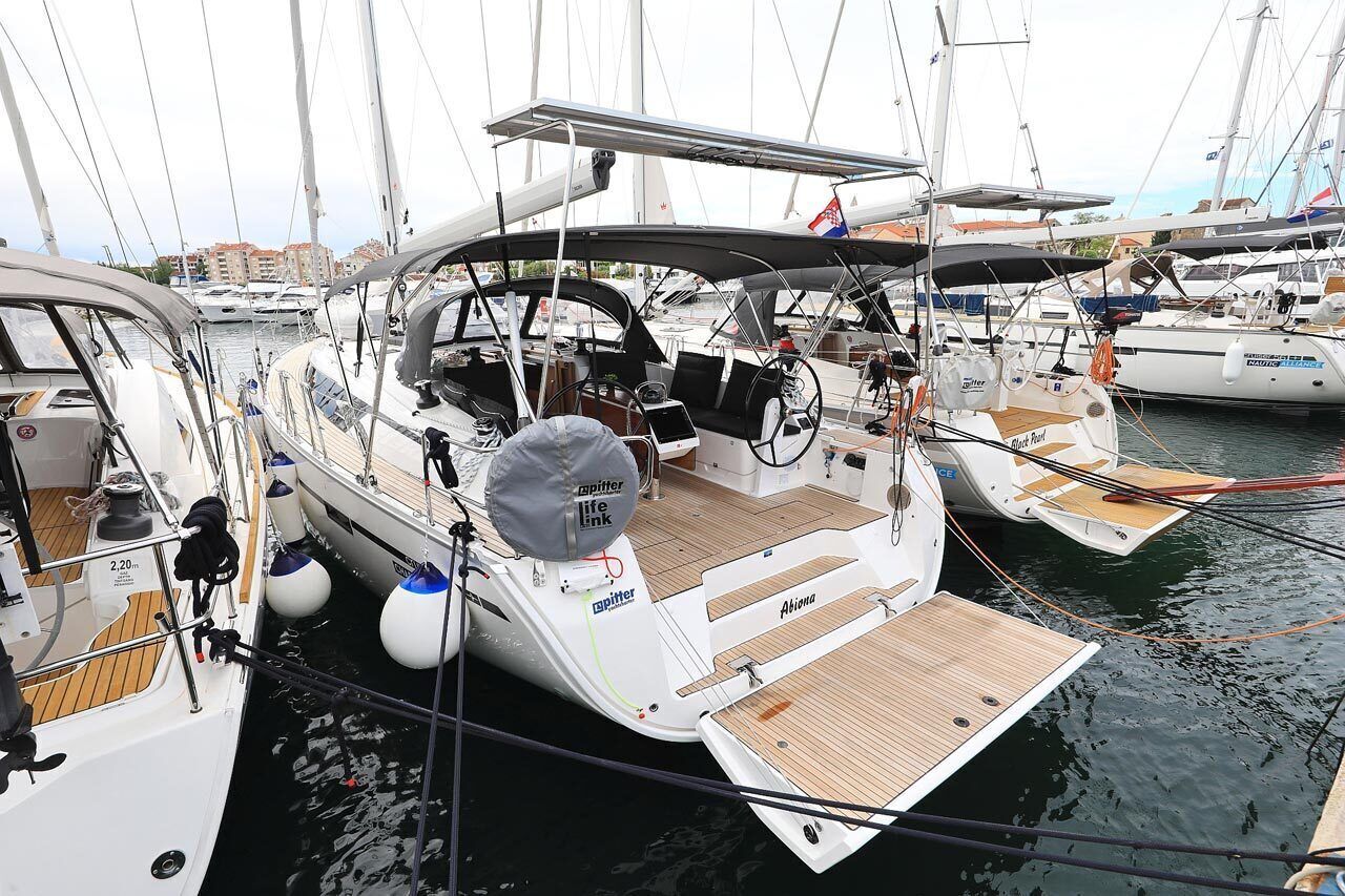 Eine Segelyacht liegt im Hafen festgemacht, mit Steuer, Steuermannschaft und einer kleinen Deckfläche.