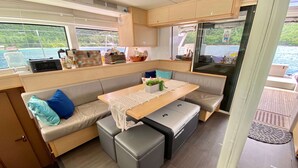 Una piccola cucina compatta con un tavolo, sedute a panchetta e vista sul mare.