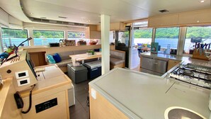 Una cucina moderna con isola centrale, una zona pranzo con divano e ampie finestre con vista sull'acqua.