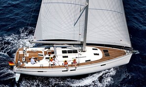 A sailboat with a deck area, passengers, and a Canadian flag. - Sun-Kissed Sailing Adventure in Islas Baleares, Mallorca (Palma)