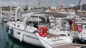 A white yacht docked at a marina with lifeboats, a website URL, and a flag. - Sun-Kissed Sailing Adventure in Islas Baleares, Mallorca (Palma)