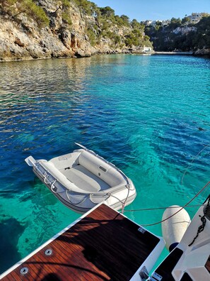 A boat anchored in clear blue water with rocky cliffs in the background. - Sun-Kissed Sailing Adventure in Islas Baleares, Mallorca (Palma)